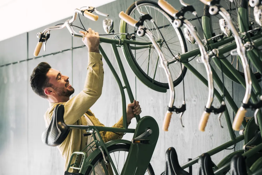 Mann hängt in einem Fahrradladen ein Fahrrad an die Wandhalterung