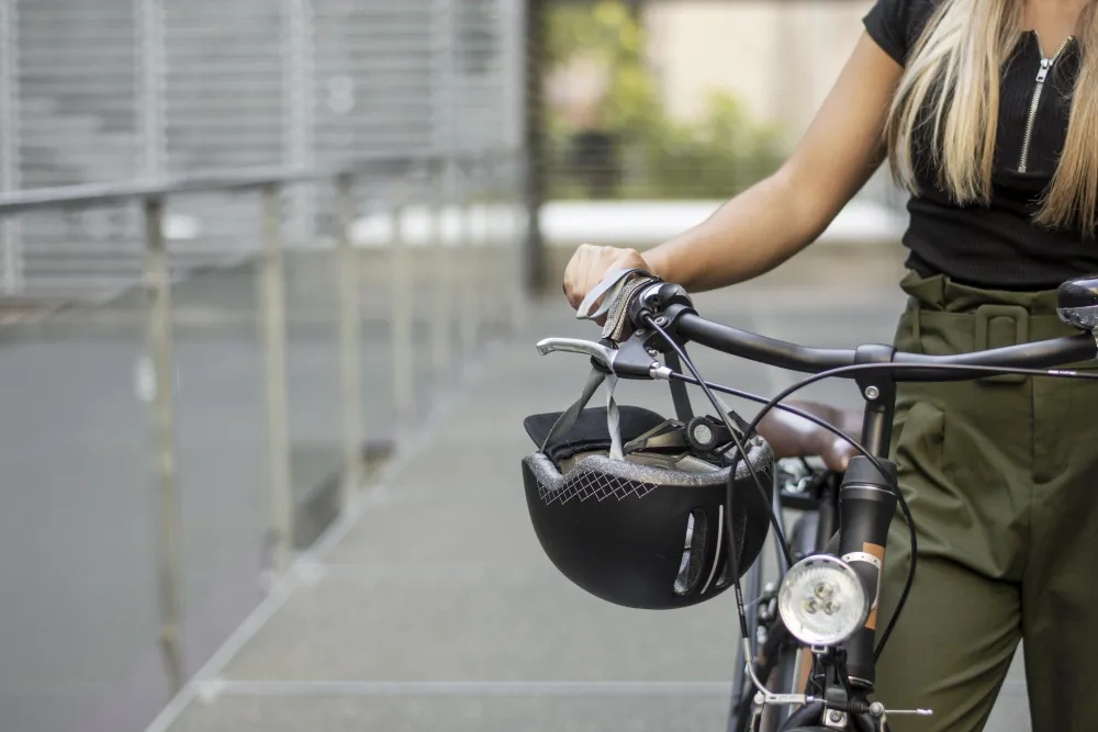 Frau mit Fahrradhelm steht neben ihrem Fahrrad