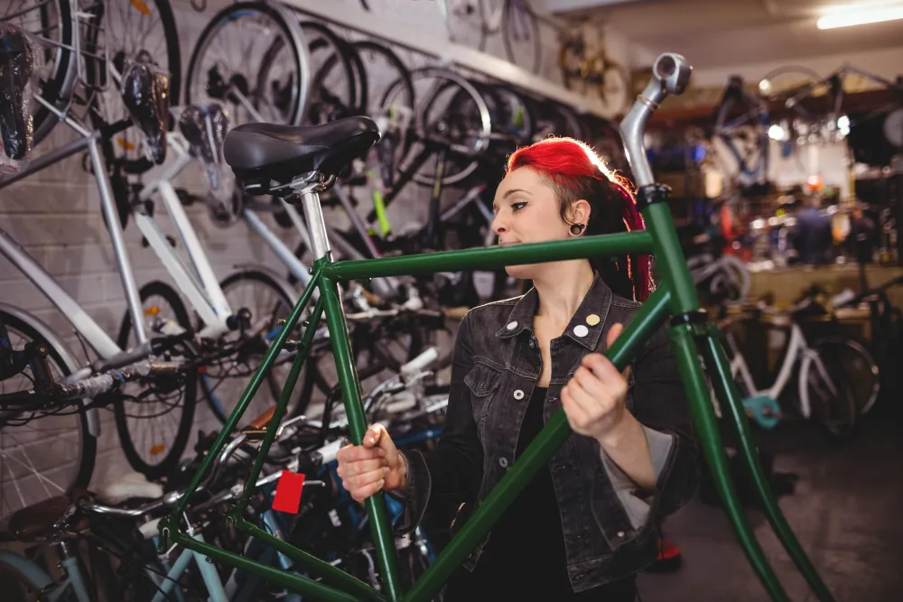 Mechanikerin arbeitet in einer Fahrradwerkstatt an einem Fahrradrahmen