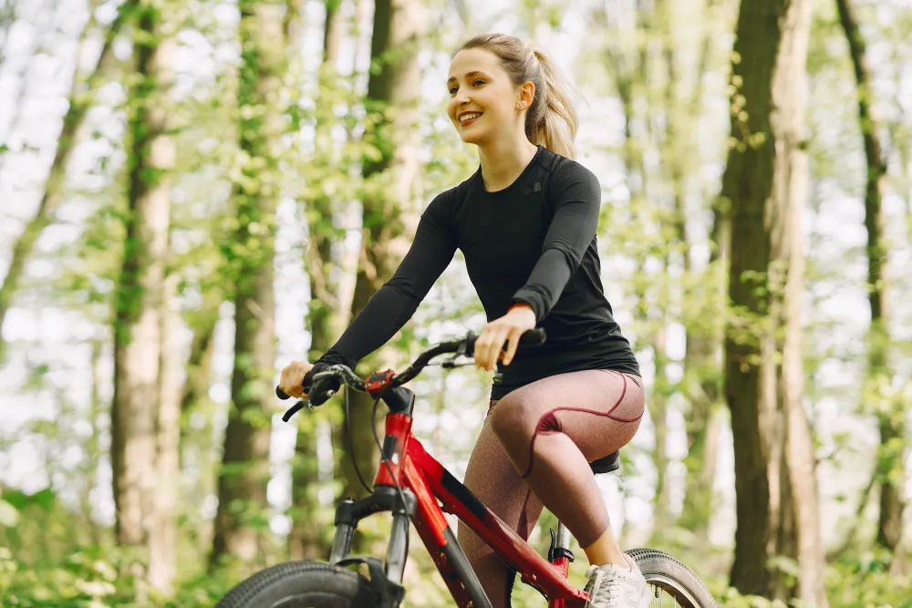 Frau fährt mit dem Mountainbike auf einem Waldweg