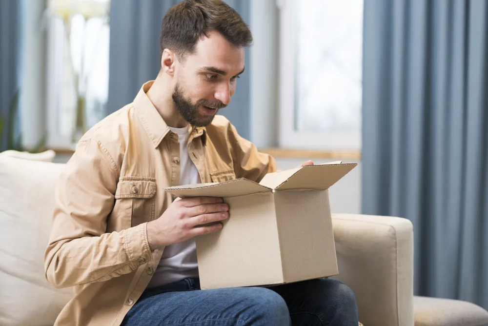 Mann öffnet zu Hause ein online bestelltes Paket