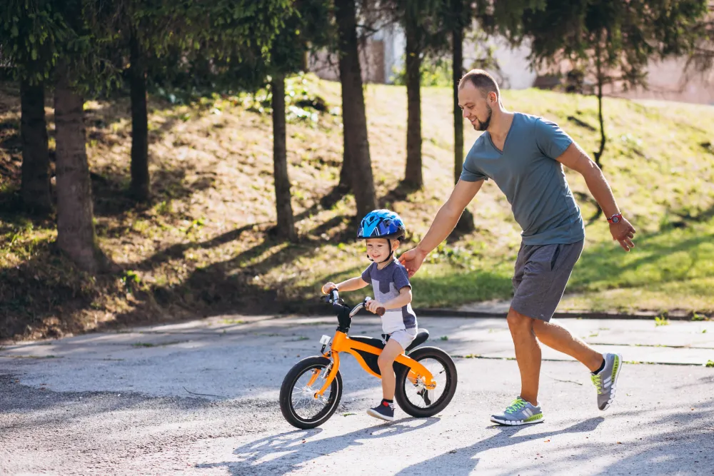 Vater hilft seinem kleinen Sohn beim Radfahrenlernen